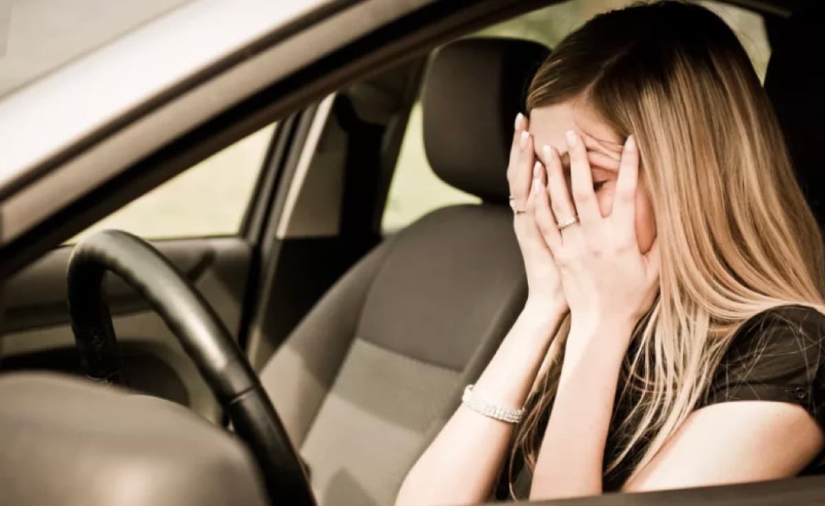 Gestreste bestuurder met de handen voor het gezicht achter het stuur